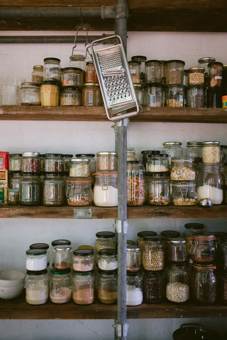 Pantry shelves lined with glass jars of dried beans, nuts and grains