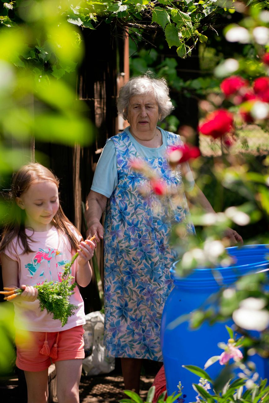 A grandmother walking with her granddaughter, who holds a bunch of just-pulled carrots